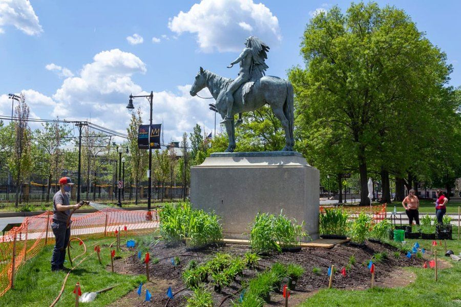 Corn and other plants surround a statue at the MFA.