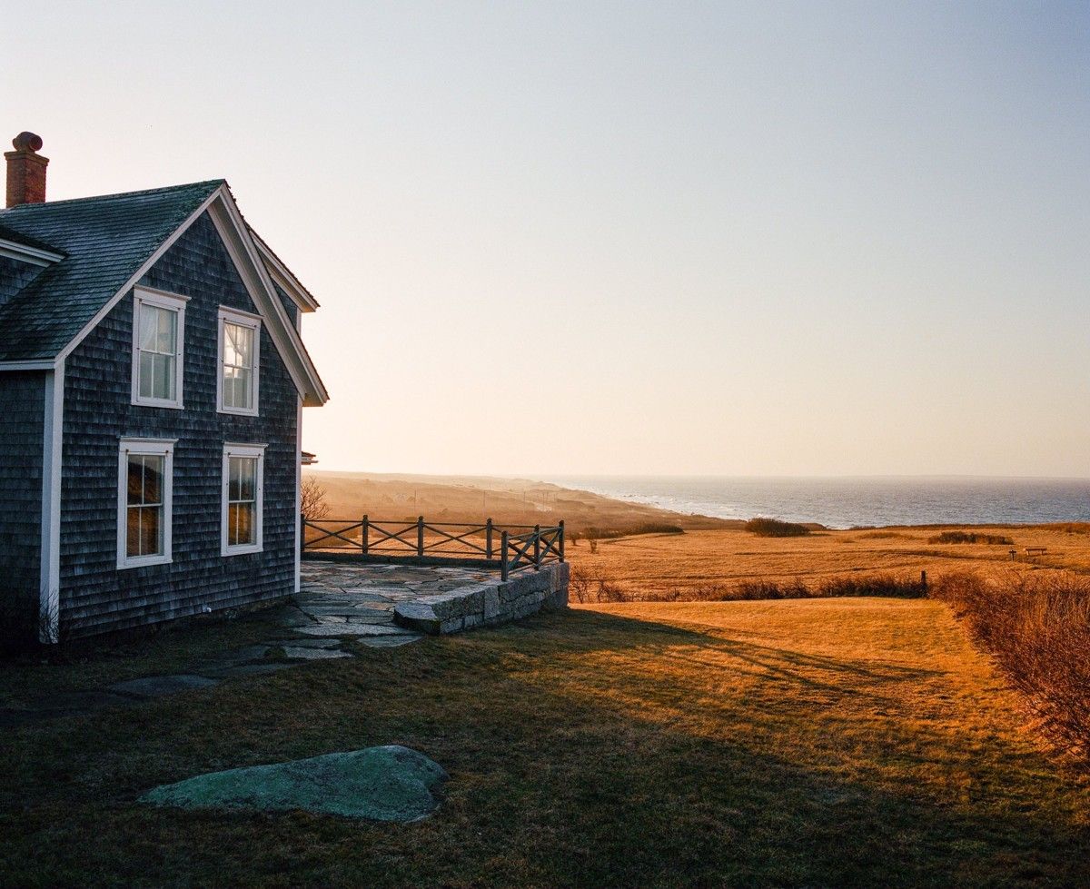 The shingled Edwin D. Vanderhoop Homestead beside open grassland and the sea in Aquinnah.