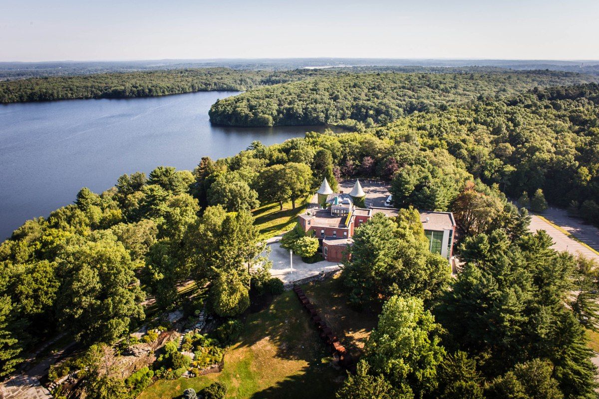 An aerial view of deCordova’s museum building, wooded grounds, and neighboring pond.